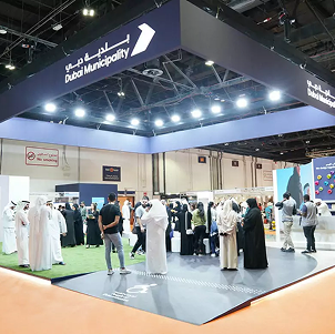 Dubai Municipality exhibition booth with visitors and interactive displays at an indoor event